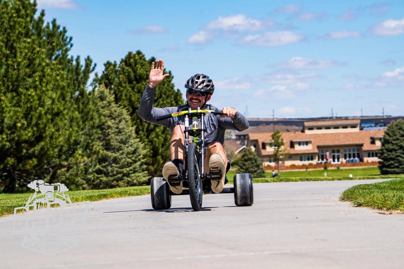 Rider waving from an adaptive trike outdoors near Sidney