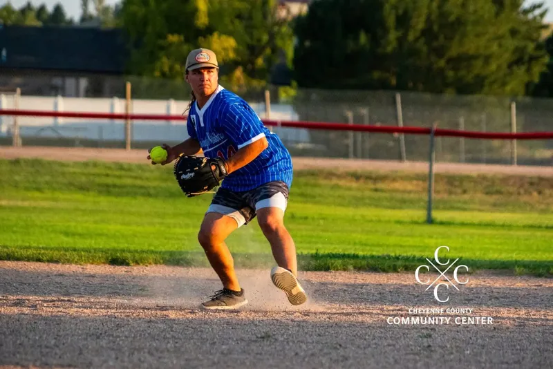 The Center co-ed softball infielder fielding a ball and setting to throw during an evening league game in Sidney, Nebraska