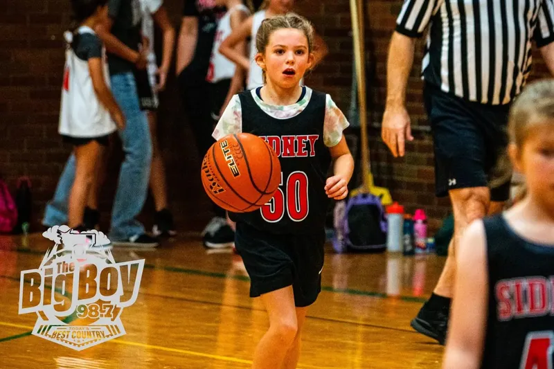 Youth basketball player in a Sidney jersey dribbling up the court during a league game at The Center