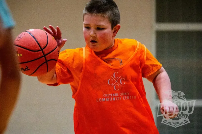 Young basketball player in an orange pinnie dribbling during a Little Swishers session at The Center