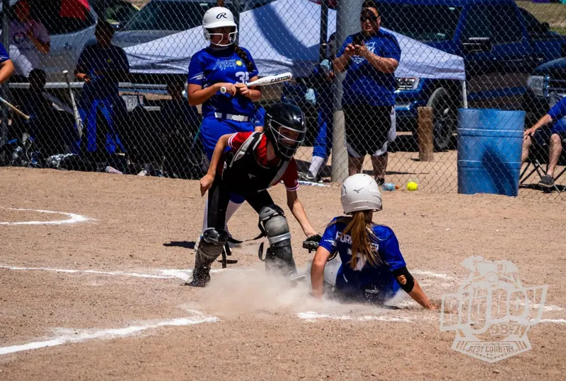 Majors Softball runner sliding safely into home plate as the catcher applies the tag during a youth softball game in Sidney, Nebraska