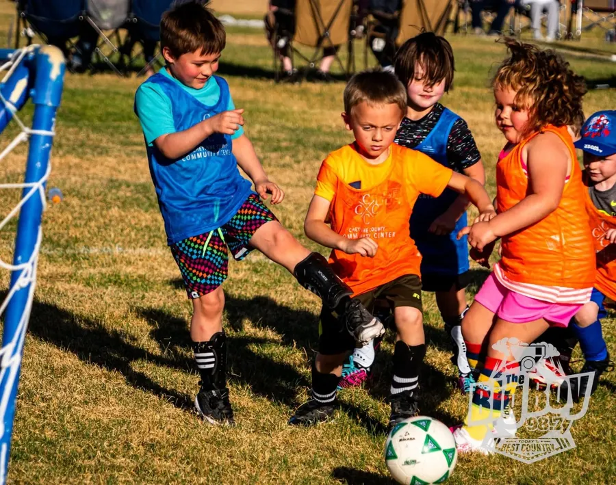 Kids in Community Center pinnies chasing the ball during a youth soccer game